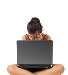  young teenage girl crying in front of the laptop on white background.